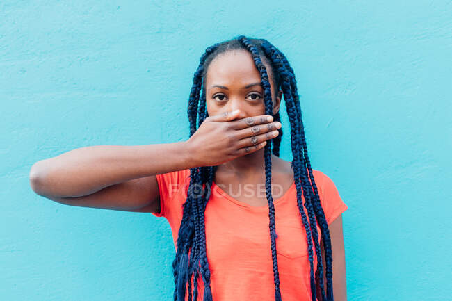 Італія, Мілан, молода жінка закриває рот перед синьою стіною. — стокове фото