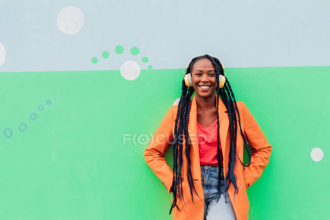 Italy, Milan, Portrait of stylish woman with headphones against wall — Stock Photo