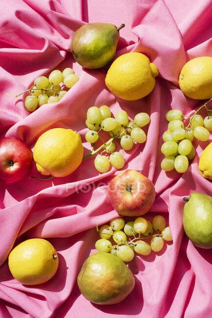 Assorted fruits on pink table cloth — Stock Photo