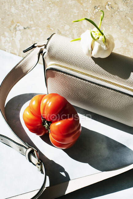 Bodegón con bolso, ajo y tomate - foto de stock