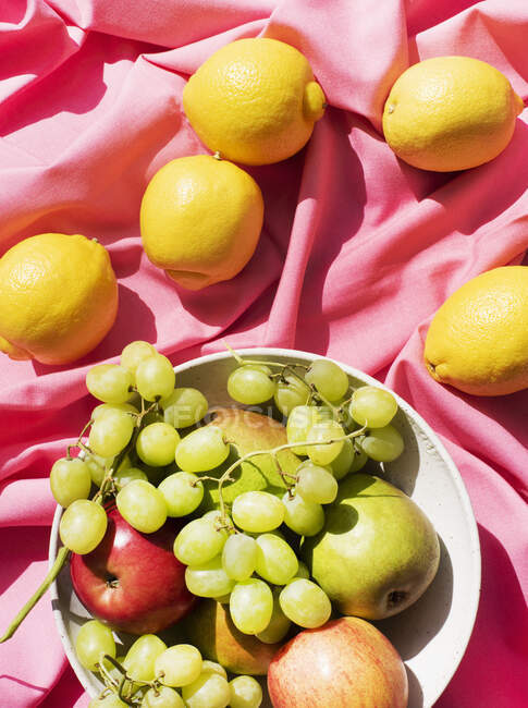 Verschiedene Früchte auf rosa Tischdecke — Stockfoto