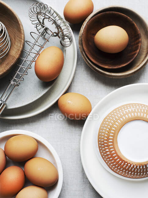 Huevos, platos, cuencos y batidor de huevos - foto de stock