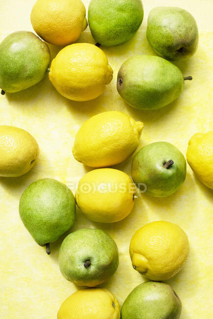 Blick auf Zitronen und Birnen auf gelbem Tischtuch — Stockfoto