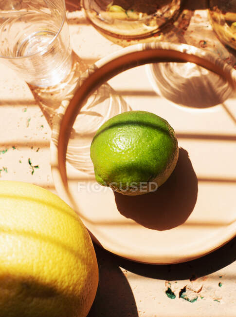 Overhead view of lime on plate and glasses — Stock Photo