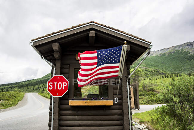 США, Аляска, американский флаг и знак остановки на каюте — стоковое фото