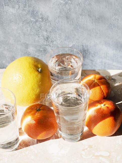 Estúdio tiro de frutas cítricas e copos de água — Fotografia de Stock