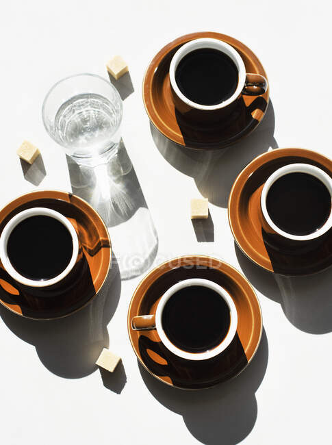 Overhead view of espresso cups and glass of water — Stock Photo
