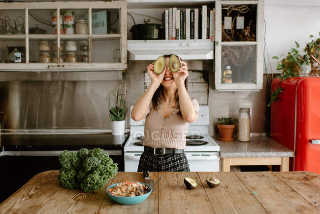 Sorrindo jovem mulher segurando abacate na frente da cara — Fotografia de Stock