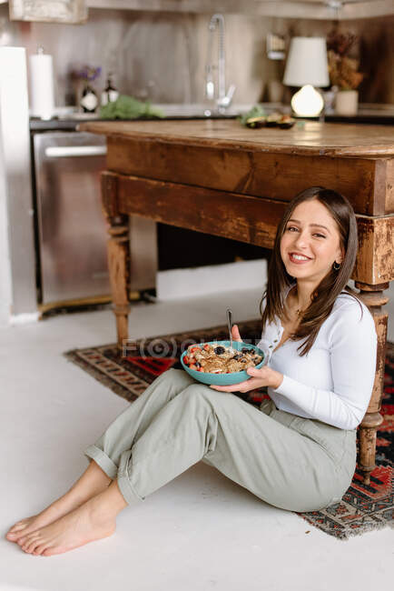 Sorridente giovane donna che tiene ciotola di muesli — Foto stock