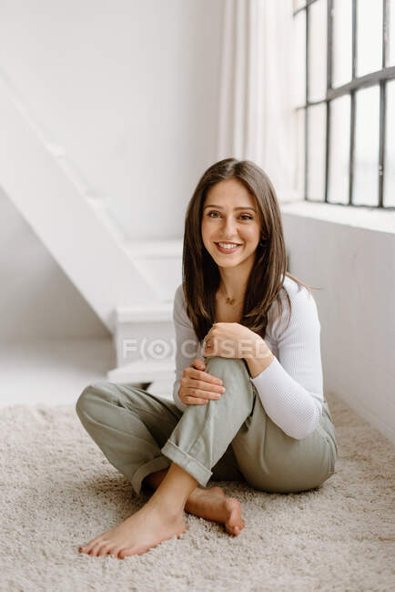Smiling young woman sitting on floor — Stock Photo