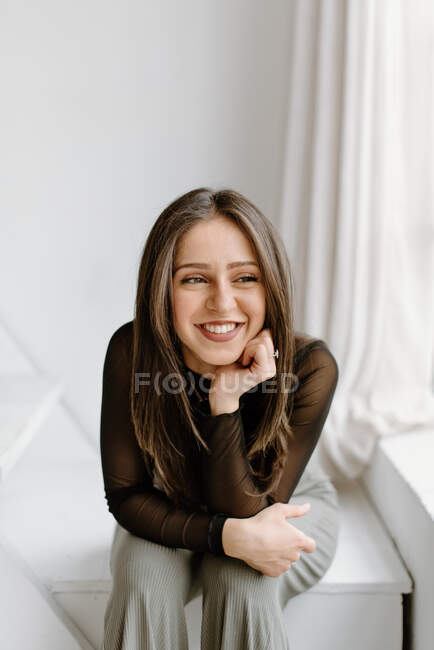 Улыбающаяся молодая женщина сидит на лестнице — стоковое фото