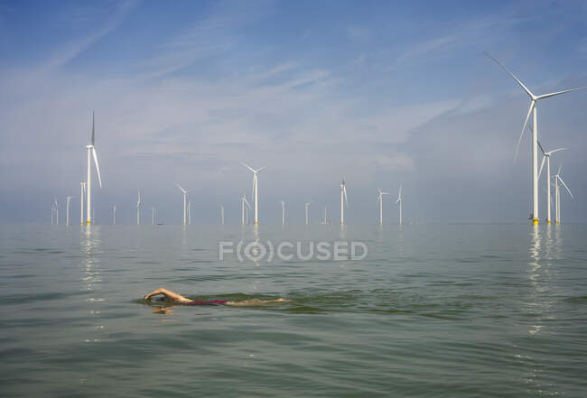 Нидерланды, Фрисланд, Бризанддик, Женщина и девочка плавают рядом с ветряными турбинами — стоковое фото