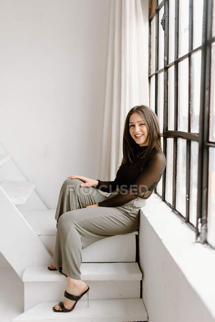 Улыбающаяся молодая женщина сидит на лестнице — стоковое фото