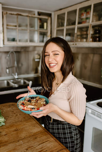 Усміхнена молода жінка тримає чашу граноли — стокове фото