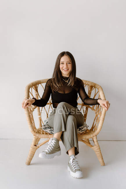 Портрет усміхненої молодої жінки, що сидить у плетеному кріслі — стокове фото