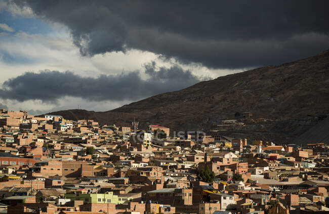 Bolivia, Potosi, Aerial view of city buildings and hill under storm clouds — Stock Photo