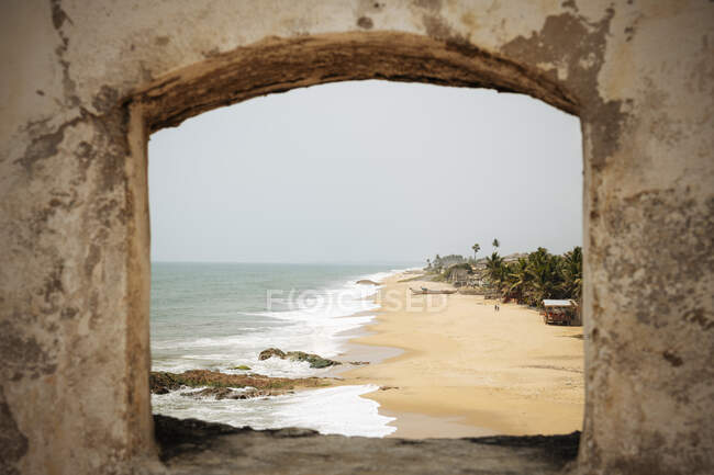 Гана, Кейп-Кост, пляж и море видны сквозь каменную арку — стоковое фото