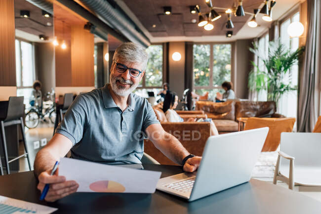 Italia, Hombre sonriente trabajando en la mesa en un estudio creativo - foto de stock