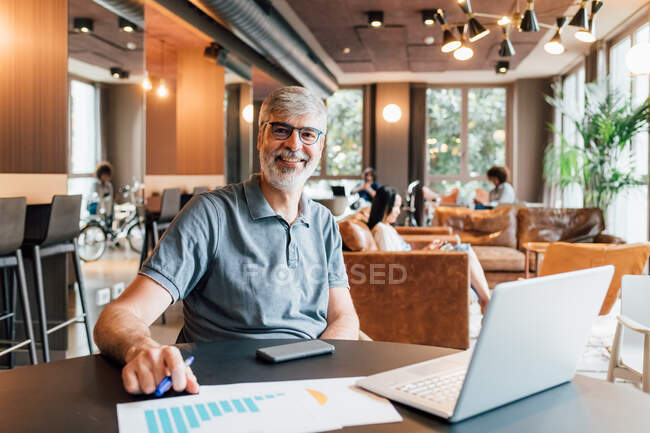 Italia, Retrato del hombre sonriente trabajando en la mesa en un estudio creativo - foto de stock