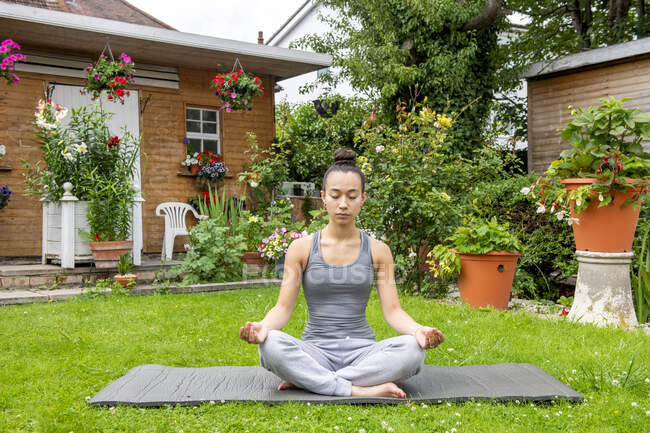 Велика Британія, Лондон, Жінка медитує на газоні перед будинком. — стокове фото