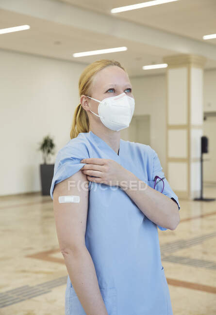 Áustria, Viena, Enfermeira em máscara facial com bandagem adesiva no braço — Fotografia de Stock
