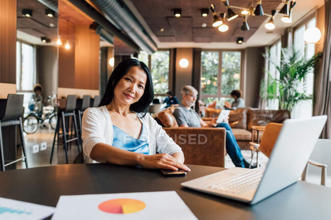 Italy, Portrait of smiling businesswoman at table in creative studio — Stock Photo