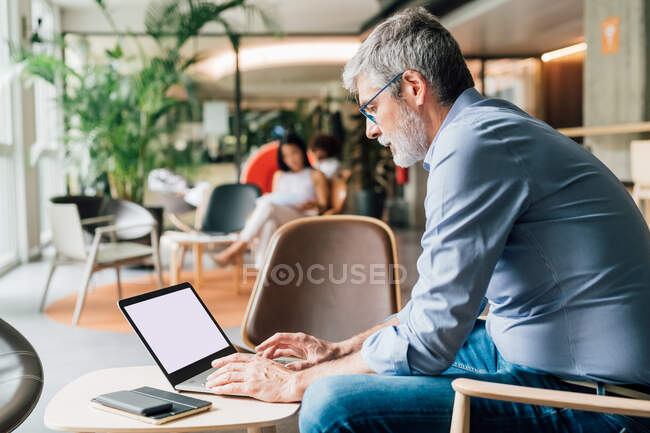 Italy, Businessman using laptop at table in creative studio — Stock Photo