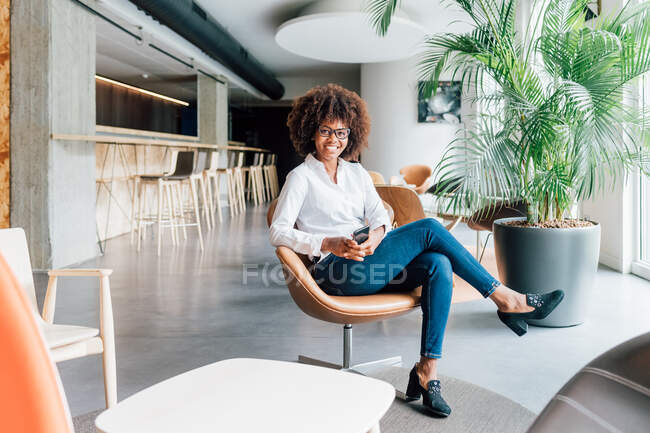 Italy, Portrait of smiling woman sitting in armchair in creative studio — Stock Photo