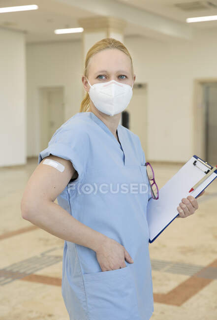 Austria, Vienna, Nurse in face mask with adhesive bandage on arm — Stock Photo