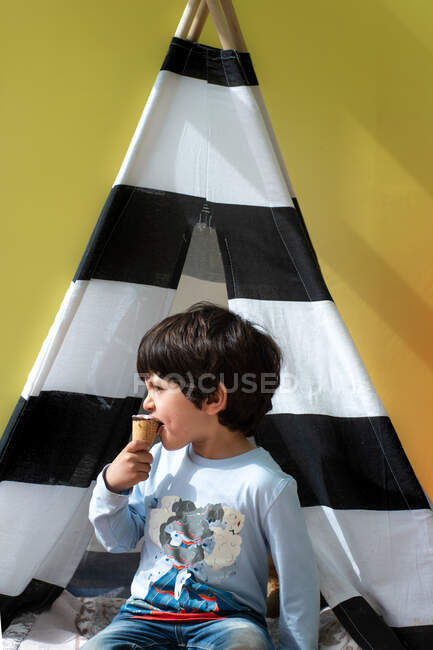 Royaume-Uni, Garçon (4-5) manger de la crème glacée devant un tipi rayé — Photo de stock