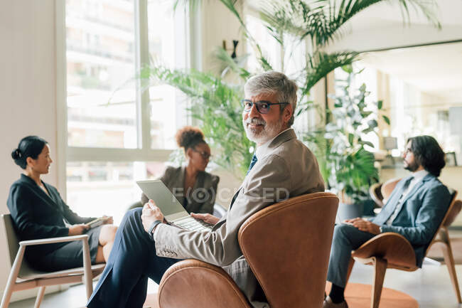 Italy, Portrait of businessman with laptop at meeting in creative studio — Stock Photo