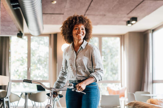 Italy, Smiling businesswoman with bicycle in creative studio — Stock Photo