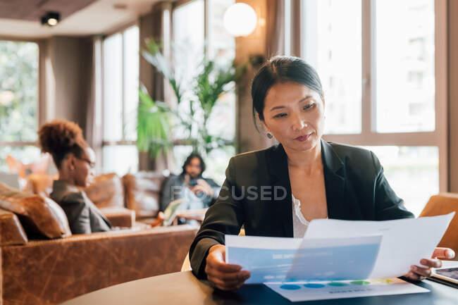Italy, Businesswoman looking at documents at table in creative studio — Stock Photo