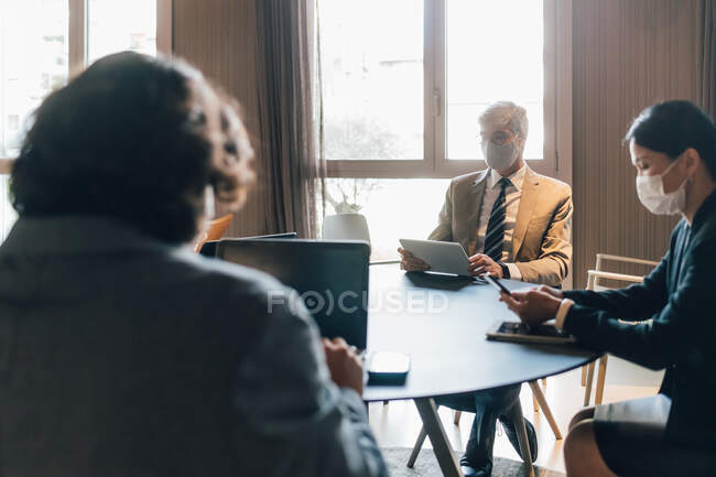 Italy, Business people in face masks having meeting in office — Stock Photo