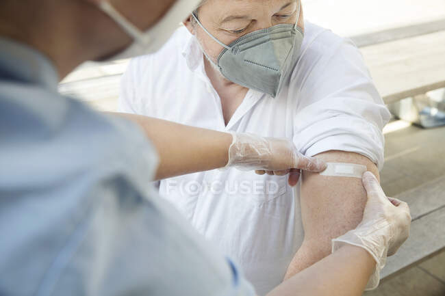 Austria, Vienna, Close-up of nurse applying adhesive bandage on patients arm — Stock Photo