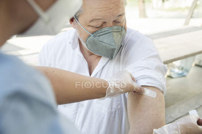 Austria, Vienna, Close-up of nurse applying adhesive bandage on patients arm — Stock Photo