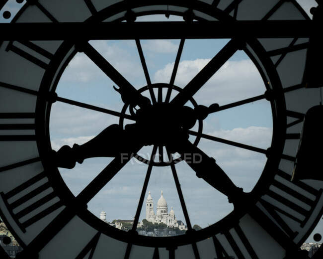 Francia, París, Primer plano del reloj con Basilique du Sacre Coeur a lo lejos - foto de stock
