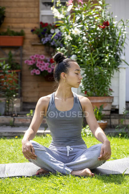 UK, London, Woman meditating on lawn in front of house — Stock Photo