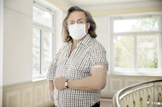 Áustria, Retrato de homem na máscara facial com bandagem adesiva no braço — Fotografia de Stock