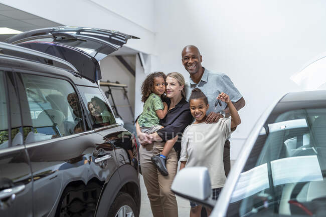 Portrait of smiling family with daughter and son in car showroom — Stock Photo