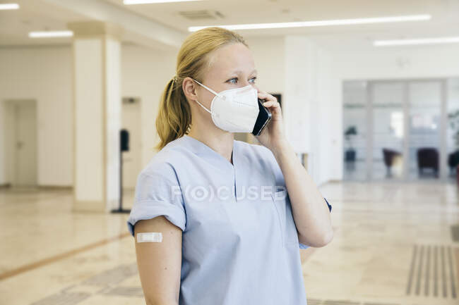 Austria, Vienna, Nurse in face mask using smart phone — Stock Photo