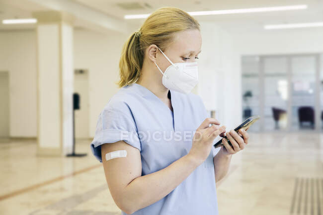 Áustria, Viena, Enfermeira em máscara facial usando telefone inteligente — Fotografia de Stock