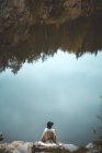 Женщина, сидящая на скалах возле озера — стоковое фото