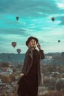 Портрет блондинки в капелюсі з повітряними кулями над містом — стокове фото