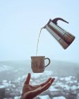 Schwebender Geysir gießt Kaffee in Becher und Männerhand — Stockfoto