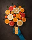 Vista superior de la composición con smartphone de mano humana con ramo de frutas cítricas — Stock Photo