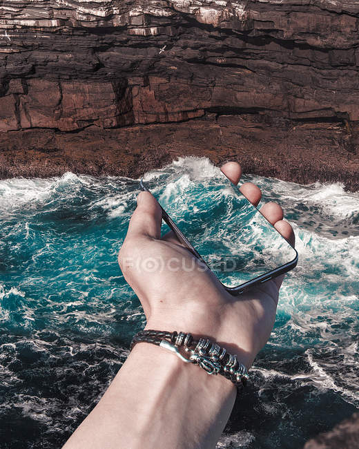 Мобильный телефон с впечатлением от океанской волны — стоковое фото