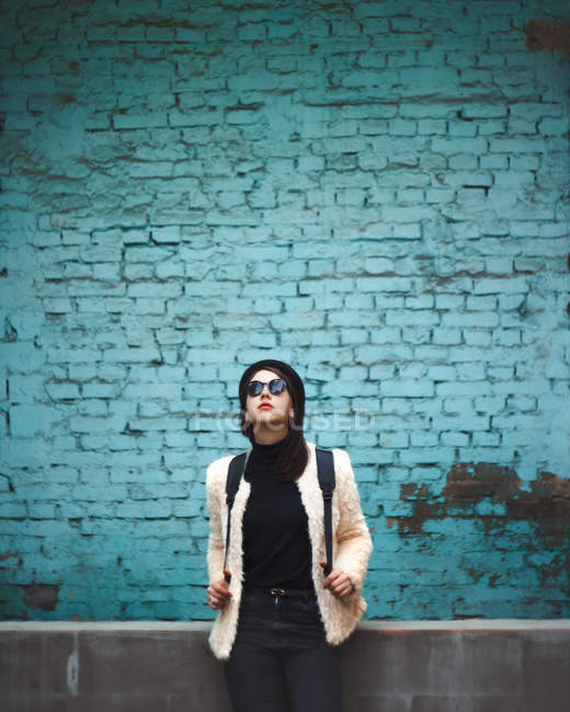 Frau mit Sonnenbrille lehnt an Wand — Stockfoto