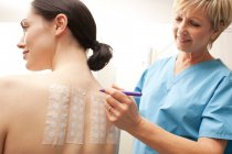 Woman undergoing allergy patch test with mature doctor. — Stock Photo