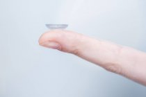 Close-up of person holding contact lens on finger. — Stock Photo